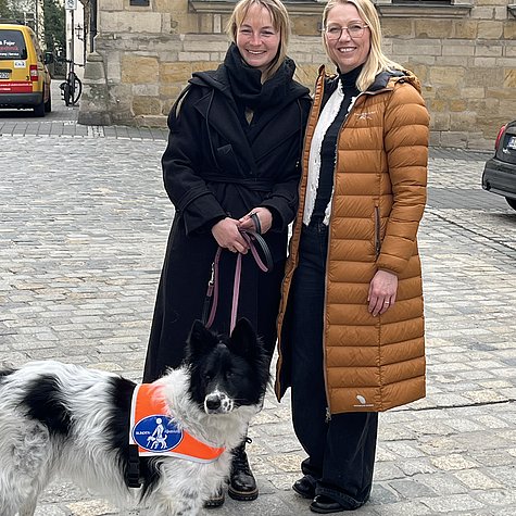 Susanne und Doreen mit Blindenführhündin Kira vor dem Gymnasium Casimirianum. – ein fröhlicher Moment voller Lebensfreude.