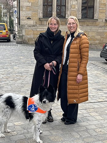 Susanne und Doreen mit Blindenführhündin Kira vor dem Gymnasium Casimirianum. – ein fröhlicher Moment voller Lebensfreude.