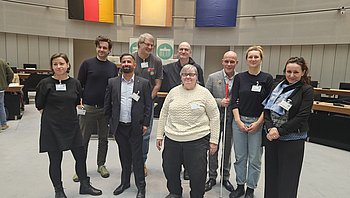 Die Teilnehmer der Fokusgruppe Sport und die politische Referentin stehen in der Mitte des Plenarsaals des Berliner Abgeordnetenhauses am Tag der Sitzung des Berliner Behindertenparlaments.