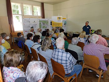 PRO RETINA berät... Im Foto sind etwa 30 Besucher bei der PRO RETINA bei der Beratung durch Roswitha Karst zu sehen.