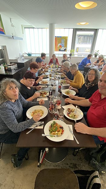 Die Teilnehmenden sitzen an einem langen Tisch im Restaurant und genießen ihr Mittagessen