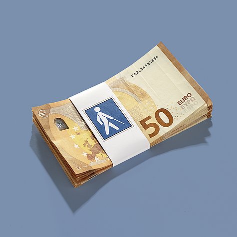 Ein Bündel 50-Euro-Scheine mit einer Banderolle, auf die eine Illustration eines Menschen mit Blindenstock gedruckt ist. 