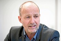 Joachim Leibiger, Thüringer Landesbeauftragter für Menschen mit Behinderungen; Quelle: Thüringer Allgemeine Zeitung Porträtaufnahme eines Mannes mit angegrautem Vollbart und in falten gelegter hoher Stirn, der ein graues Sacco trägt und darunter ein weiß-blau kariertes Hemd.