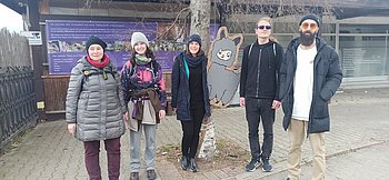 Gruppenbild mit fünf Personen. Im Hintergrund sieht man einen Holz-Aufsteller in Form eines Alpakas.