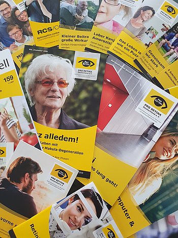 Verschiedene gelb gestaltete Broschüren und Ratgeber von PRO RETINA liegen ausgebreitet nebeneinander.