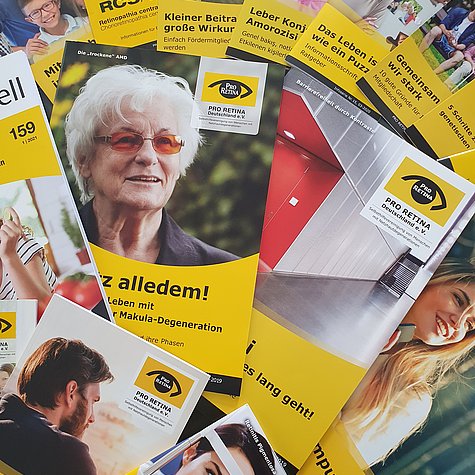 Verschiedene gelb gestaltete Broschüren und Ratgeber von PRO RETINA liegen ausgebreitet nebeneinander.