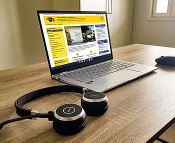Digitalisierung ©PRO RETINA Laptop, auf dem PRO RETINA-Seite geöffnet ist. Daneben liegen Kopfhörer.