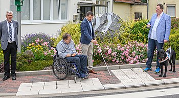 Benedikt Bauch (Bildmitte), Leiter der Arbeitsgruppe, erklärt die einzelnen Einbauten für eine barrierefreie Querung der Straße; mit dabei Bernd Winkler, Leiter des Geschäftsbereichs Planung/Bau im LBM RP (links im Bild), Matthias Rösch, Landesbeauftragter für die Belange behinderter Menschen (2. v. li.), und Wolfgang Schweinfurth, Fachberater für Barrierefreiheit, PRO RETINA Deutschland e.V. (Quelle: LBM)