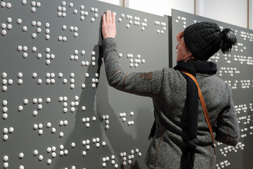 Anne ertastet den Text an den Tafeln von Adi Hoesle.