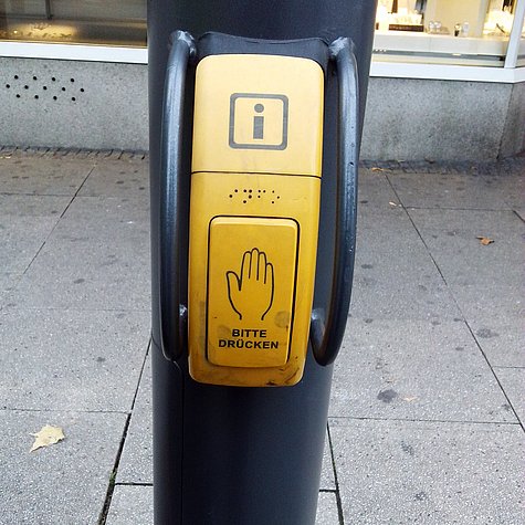 Barrierefreie Ampel Kleiner gelber Kasten mit Hand-Symbol an einer Informationsstele