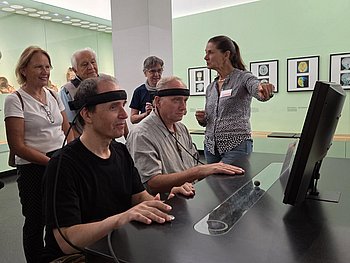Steffen und Alejandro mit Messgerätband um die Stirn vor einem Monitor