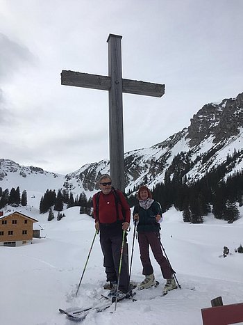 Elo Schröder-Hanisch mit ihrem Mann beim Skifahren vor einem Gipfelkreuz 