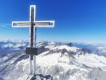 Gipfelkreuz auf dem Großvenediger mit Blick über die Alpenlandschaft.