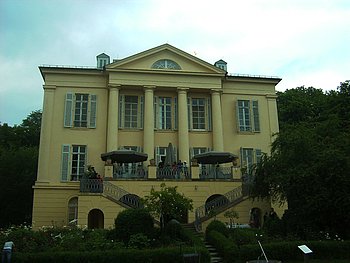 Ein imposantes gelbes Gebäude mit Säulen an der vorderen Fassade