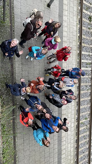 Die gesamte Gruppe am Bahnsteig, nach oben schauend und winkend.
