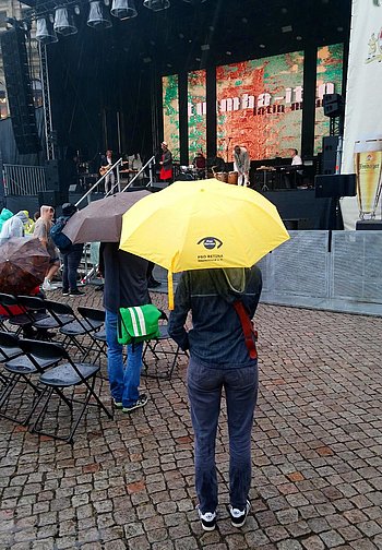 Gelber Pro Retina Regenschirm vor Bühne