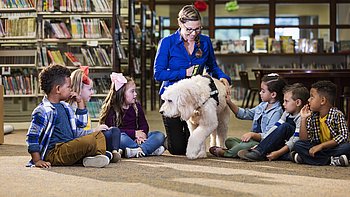 Children in library with reading assistance dog