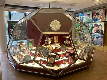 Eineriesige Vitrine in Form eines Fußballs. Darin stehen die Pokale