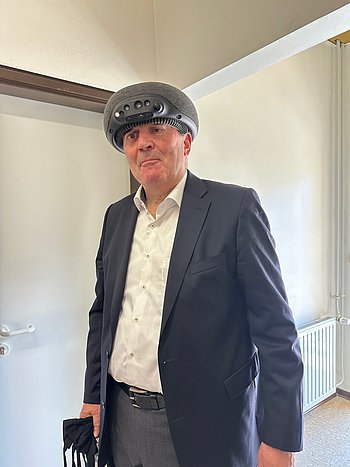 Bernd Neubauer testet beim BFW, in Düren, das „Superbrain“, das den Raum vor einem über Sensoren detektiert und vor Hindernissen warnt. Es wird, ähnlich einem Turban, auf dem Kopf getragen und gibt spürbare Signale auf die Stirn.