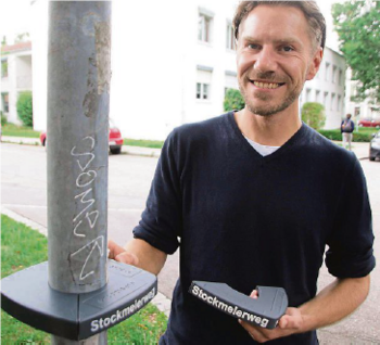 Ein junger blonder Mann steht an einem Straßenschild