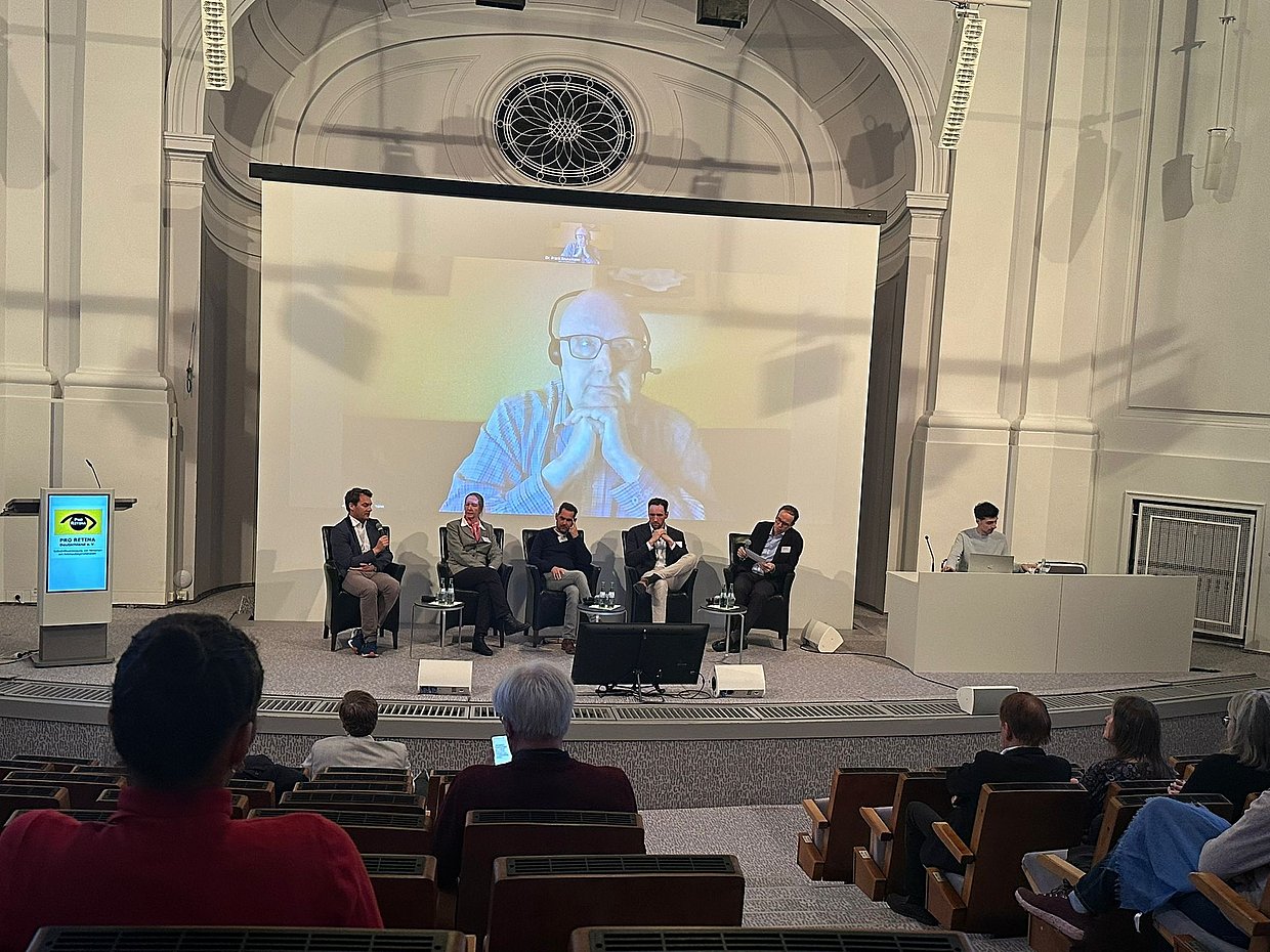 Die Referentin und die Referenten sitzen während der Podiumsdiskussion im Halbkreis auf der Bühne.