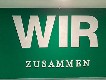 Schrift auf grünem Hintergrund: WIR zusammen