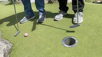 Minigolfbahn mit vier Füßen, zwei Schlägern und einem Ball