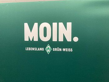 Schrift auf grünem Hintergrund: MOIN. Darunter steht Werder Bremen
