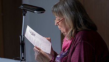 Eine Frau mit Brille ließt unter eine kleinen Lampe. (Bild: Andreas Friese)