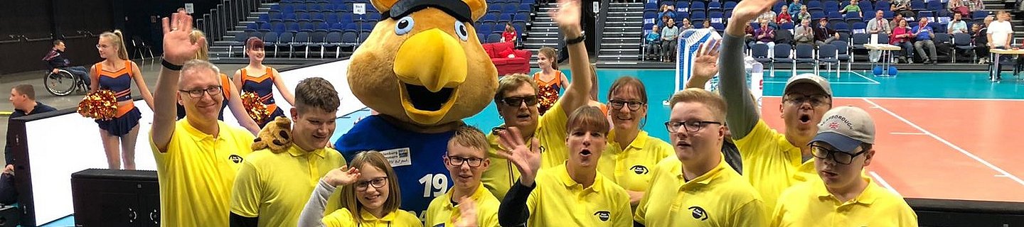 PRO RETINA bei der Goalball-EM Eine Gruppe junger Menschen mit gelben Poloshirts mit PRO RETINA-Logo steht in einem Stadion. Im Hintegrund besetzte Zuschauerränge.