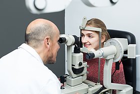 Eine junge Frau sitzt beim Augenarzt, bei ihr wird eine Augenuntersuchung durchgeführt