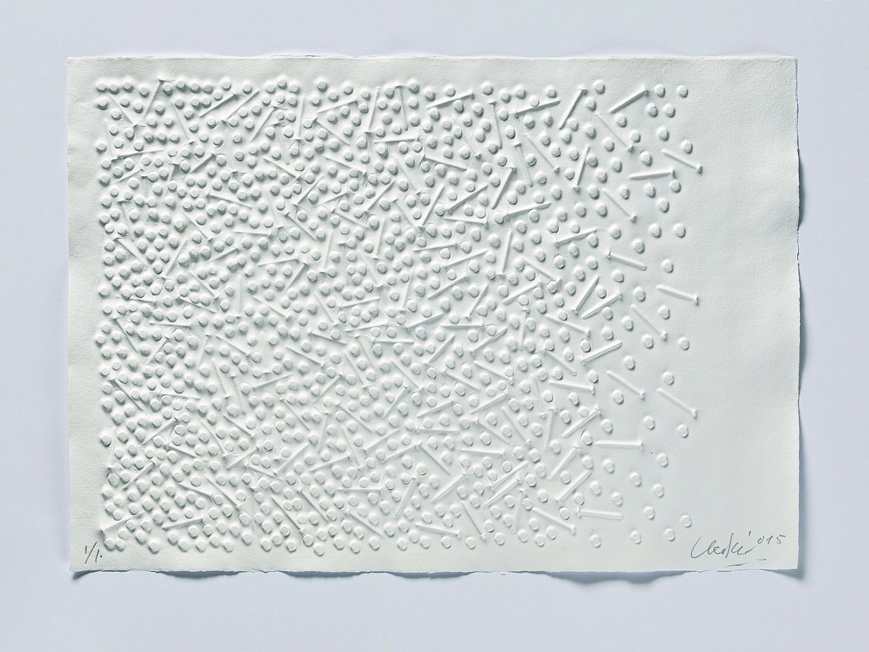 Das Kunstwerk zeigt ein weiß bemaltes Relief aus Nägeln, das durch die Wechselwirkung von Licht und Schatten eine besondere Dynamik entfaltet.