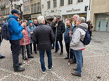 Foto: Zu sehen sind die Teilenhemer der Führung der Himmelsleiter. Sie stehen in einem Halbkreis um den Führer und hören gespannt zu